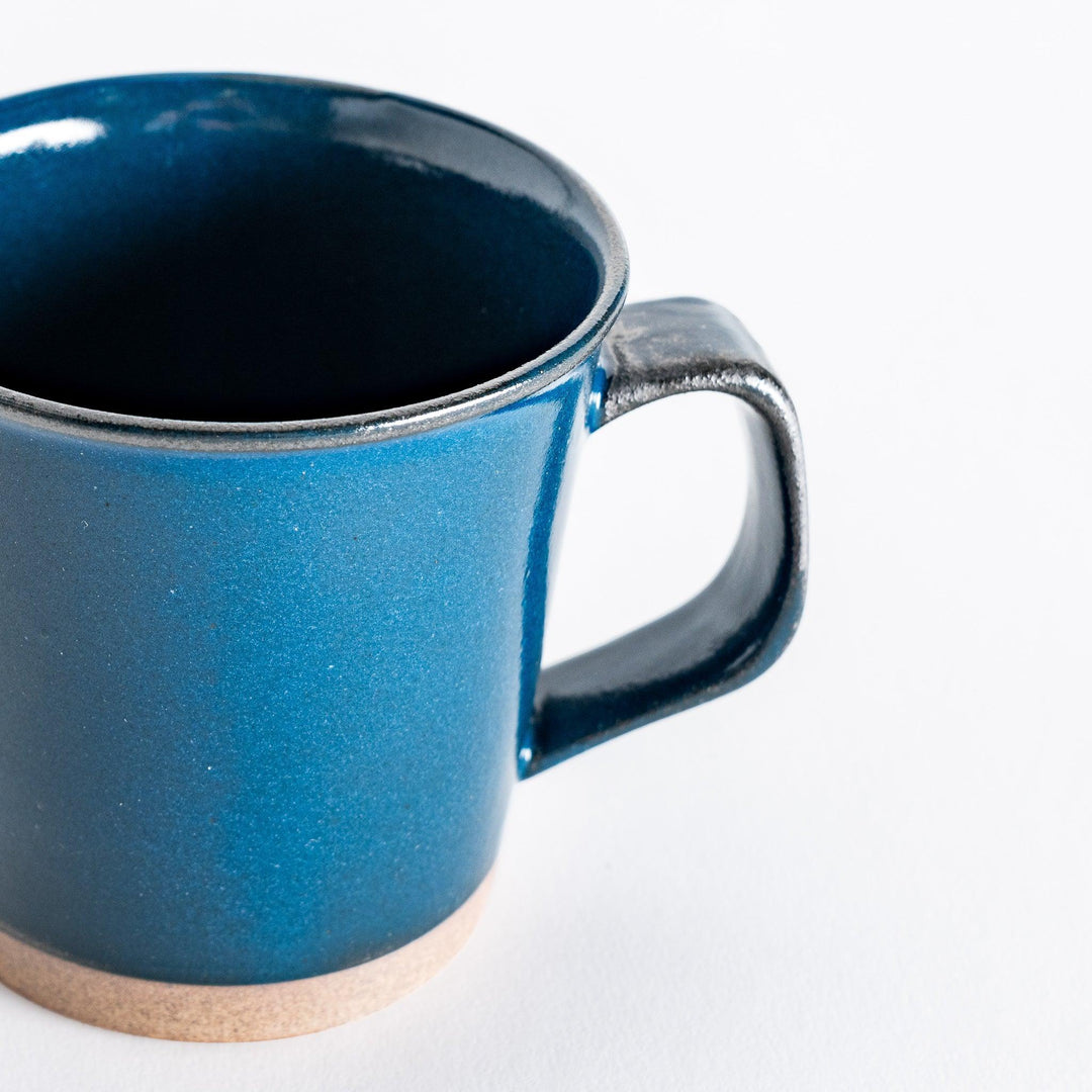 Close-up of a blue ceramic mug focusing on the glossy blue finish and the subtle texture of the base.