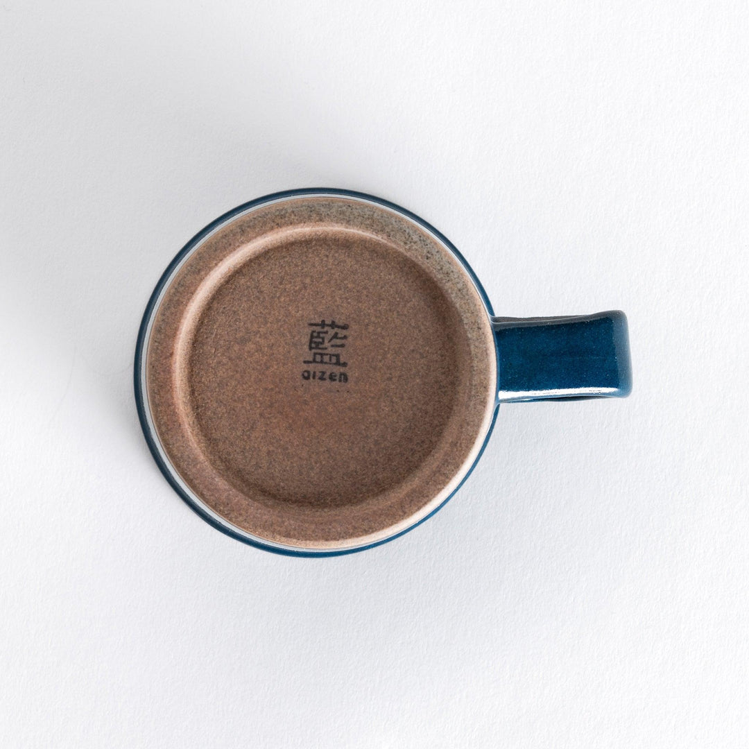 Bottom view of a blue ceramic mug with a neutral-toned, slightly textured base, adding contrast to the glossy blue surface.
