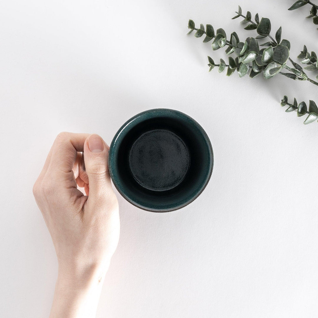 Top-down view of a green ceramic mug held in hand, showing the spacious opening and smooth interior.
