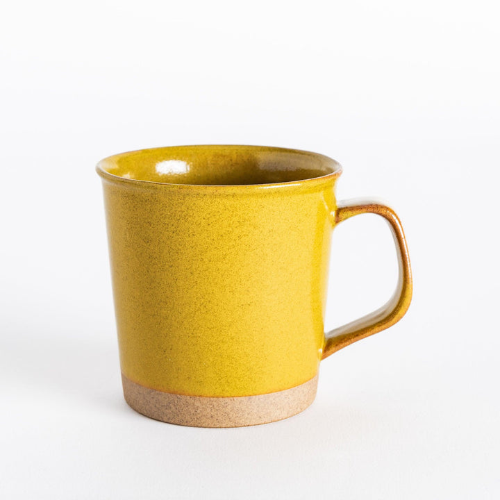 Front view of a yellow ceramic mug with a glossy finish and neutral-toned base, presenting its cheerful, modern design.