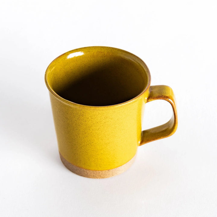 Slightly angled view of a yellow ceramic mug, capturing its smooth handle and vibrant yellow glaze.