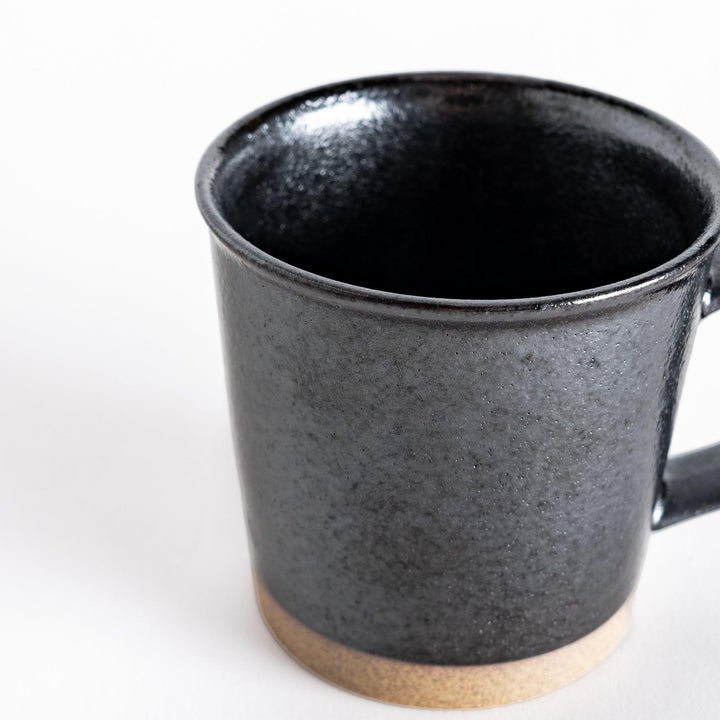 Close-up view of the black ceramic mug, highlighting the glossy finish and neutral-toned base.