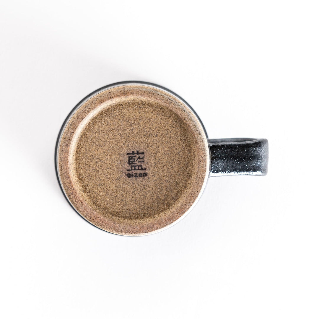 Bottom view of the black ceramic mug, featuring the smooth neutral-toned base and clean design.