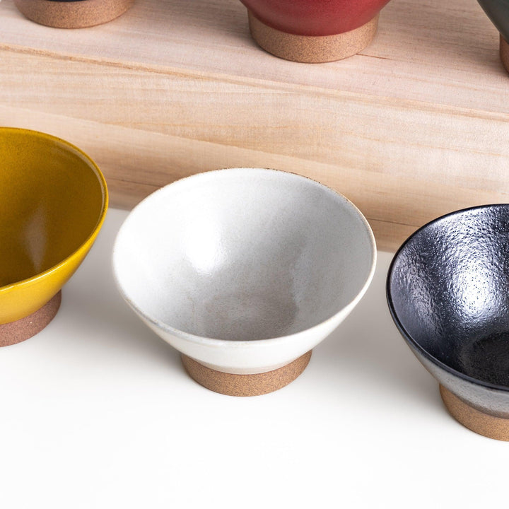 Ceramic rice bowl with smooth glossy finish and natural clay base placed on wooden block for modern dining.