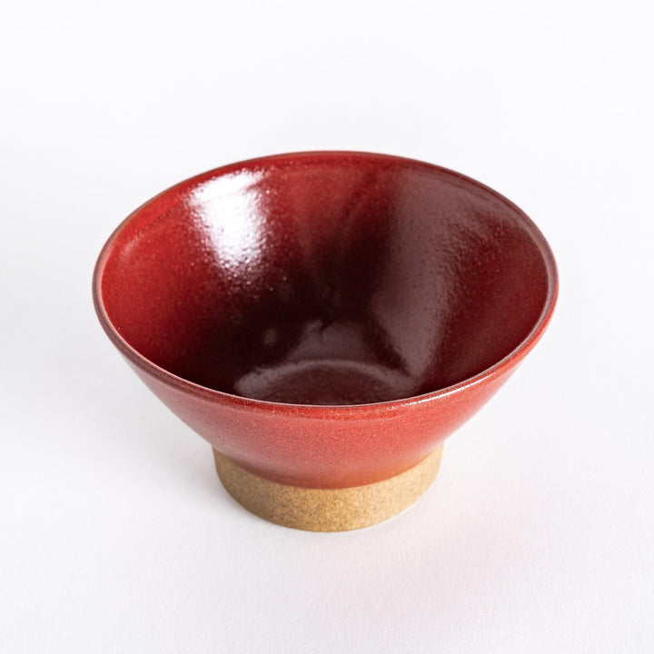 Red ceramic rice bowl with a glossy glaze, photographed at a slight angle to showcase its depth and shine.