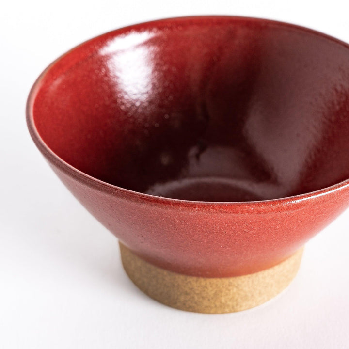 Close-up of the red ceramic rice bowl, focusing on its vivid color, smooth surface, and neutral-toned base.