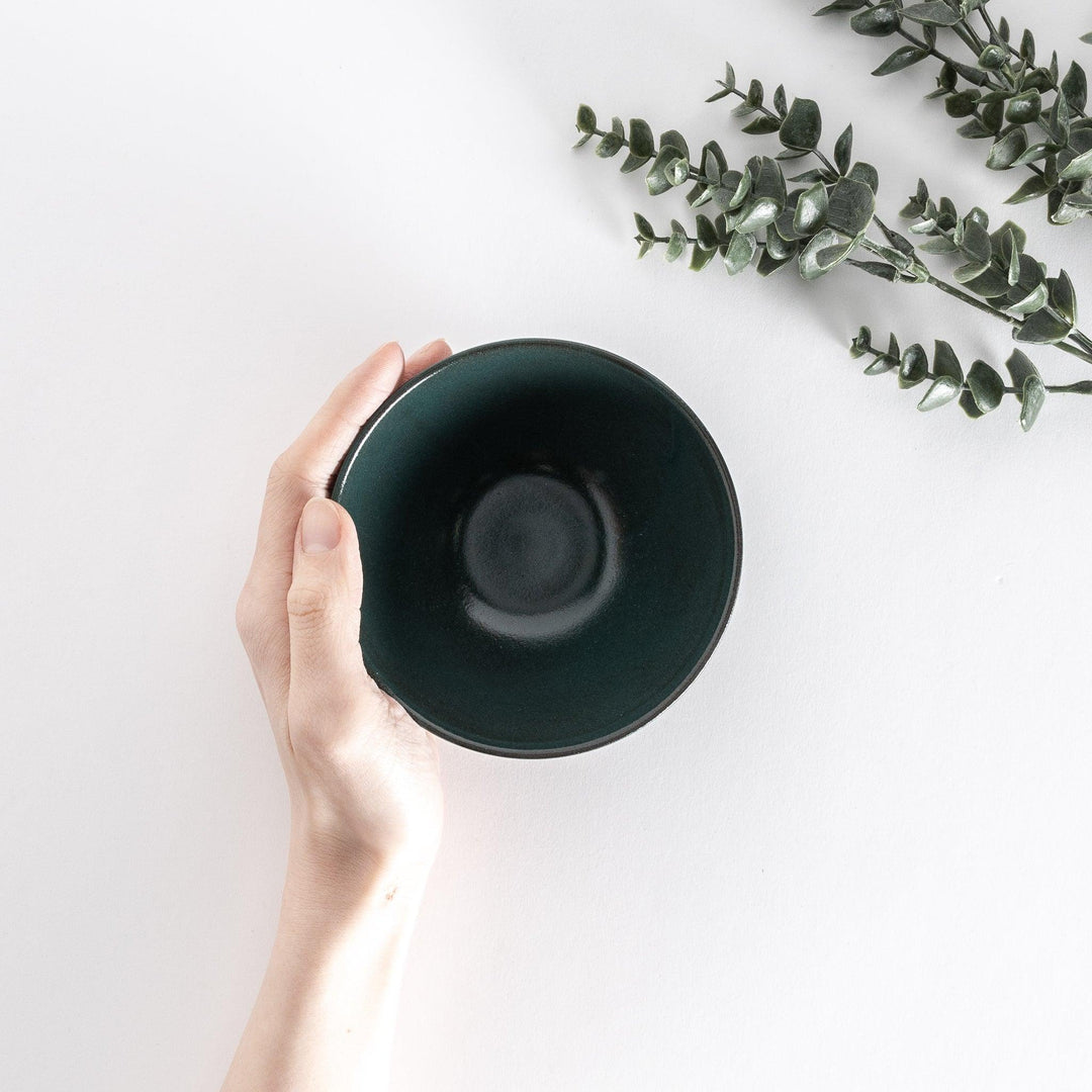 Green ceramic rice bowl held by hand, viewed from above to showcase its rich green interior and smooth glaze.