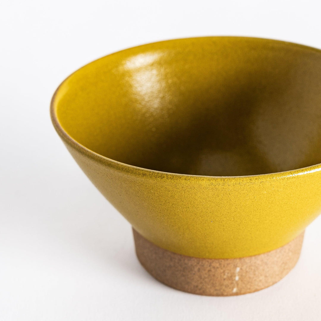 Close-up view of the yellow ceramic rice bowl, focusing on its smooth glossy finish and neutral-toned base.