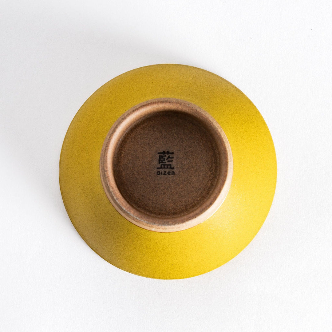 Bottom view of the yellow ceramic rice bowl, showcasing its sturdy neutral-toned base and clean finish.