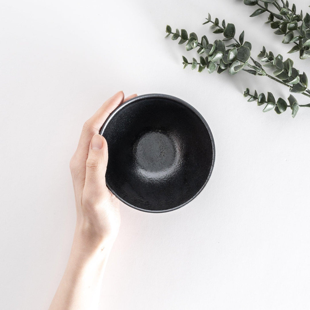 Black ceramic rice bowl with a glossy glaze, photographed at a slight angle to highlight its curves and design.