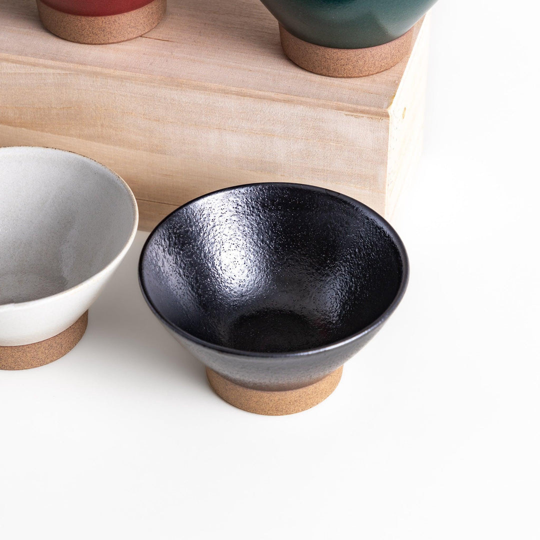 Ceramic rice bowl with smooth glossy finish and natural clay base placed on wooden block for modern dining.