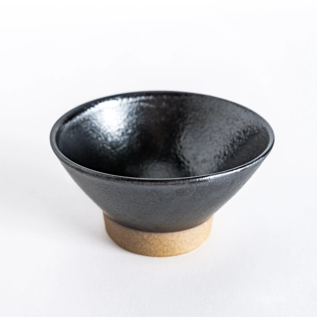Black ceramic rice bowl held by hand, viewed from directly above to showcase its smooth interior.