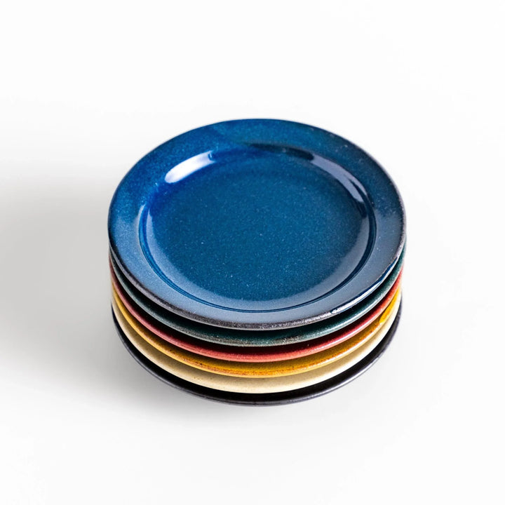 Stack of five colorful Japanese sauce dishes in blue red green yellow and black with glossy finish.