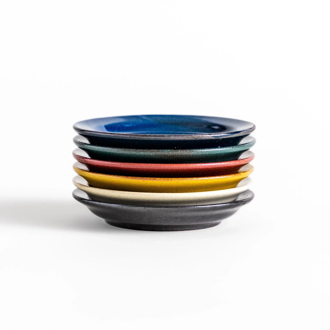 Stack of five colorful Japanese sauce dishes in blue red green yellow and black with glossy finish.