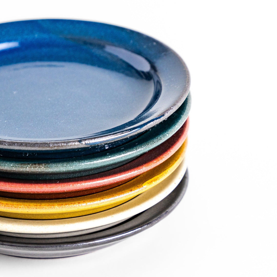 Stack of five colorful Japanese sauce dishes in blue red green yellow and black with glossy finish.
