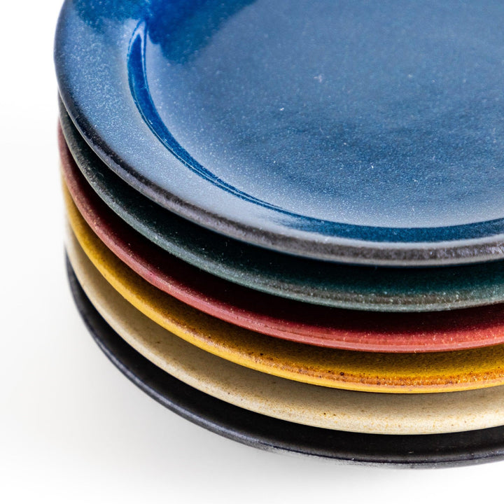 Stack of five colorful Japanese sauce dishes in blue red green yellow and black with glossy finish.