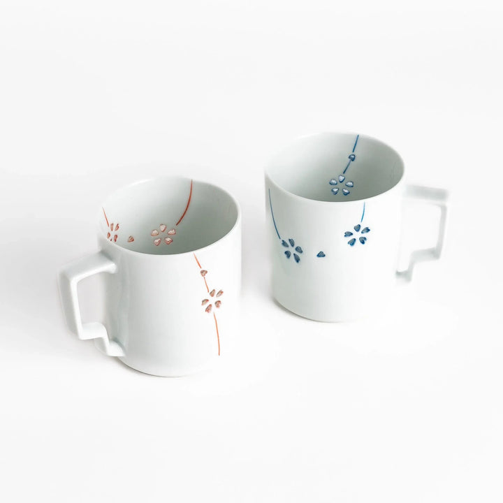 Ceramic mug pair with delicate red and blue floral designs perfect for adding elegance to your morning coffee.
