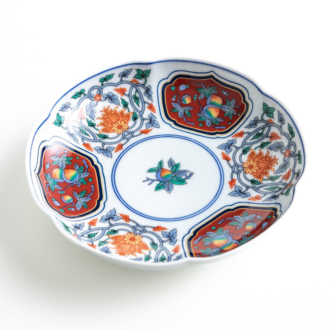 Round dessert plate with floral center and scalloped rim featuring red green and gold intricate patterns.