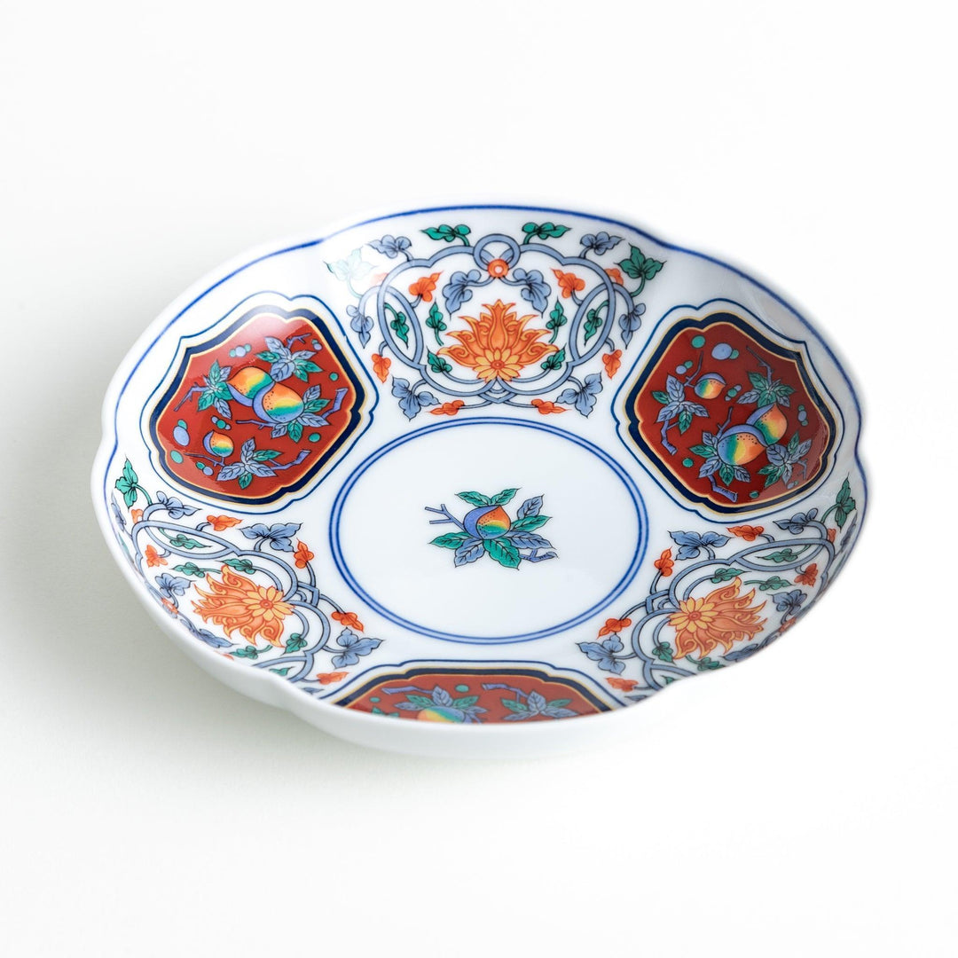 Round dessert plate with floral center and scalloped rim featuring red green and gold intricate patterns.