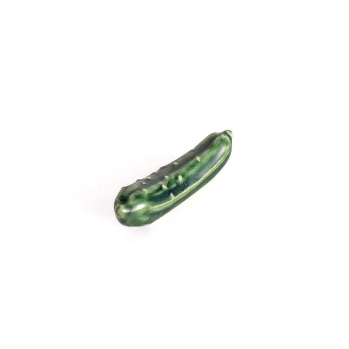 Glossy green ceramic cucumber chopstick rest with textured details adding playful accent to dining table.