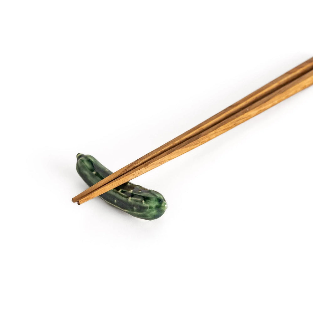 Glossy green ceramic cucumber chopstick rest with textured details adding playful accent to dining table.