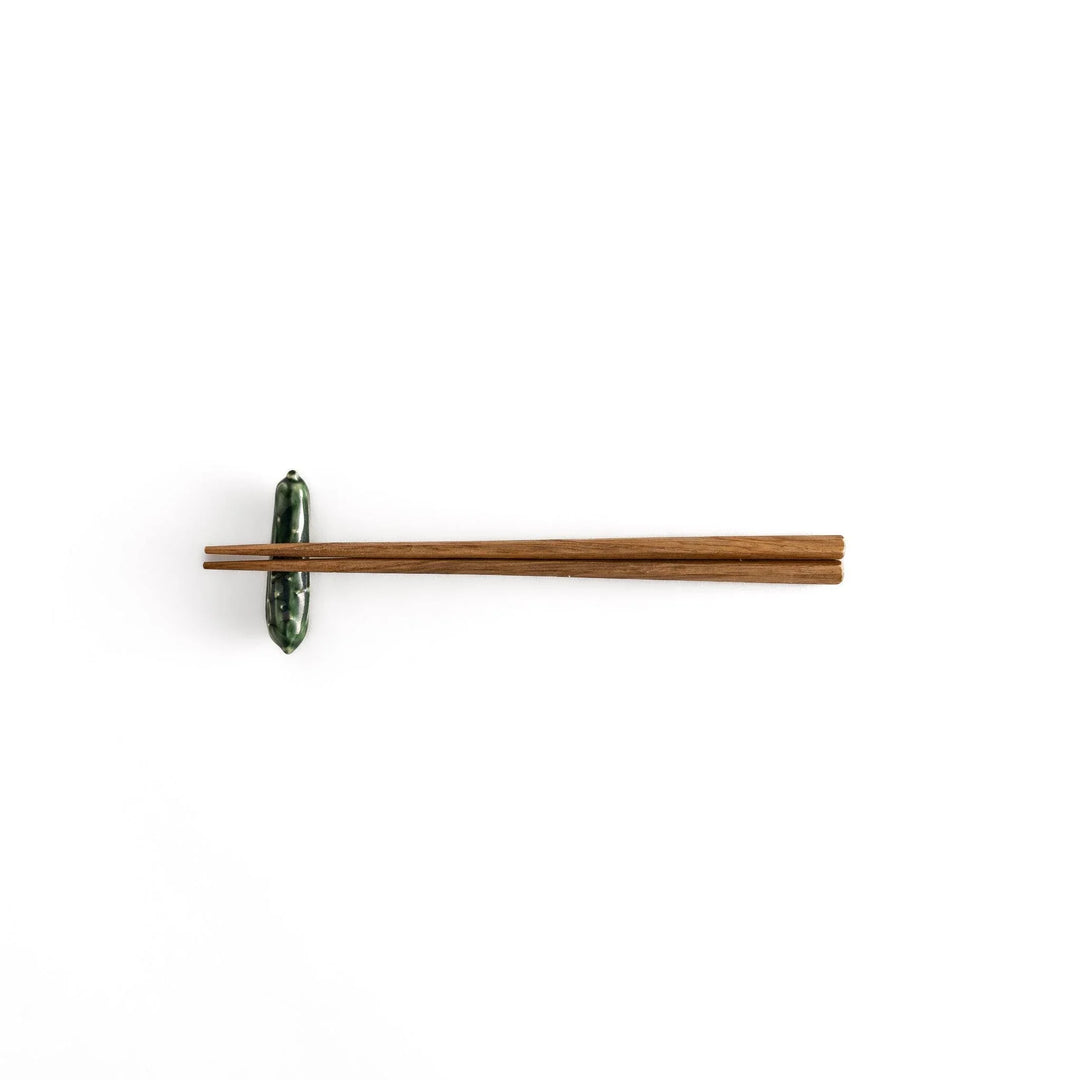 Glossy green ceramic cucumber chopstick rest with textured details adding playful accent to dining table.