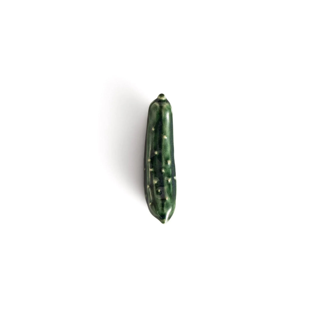Glossy green ceramic cucumber chopstick rest with textured details adding playful accent to dining table.