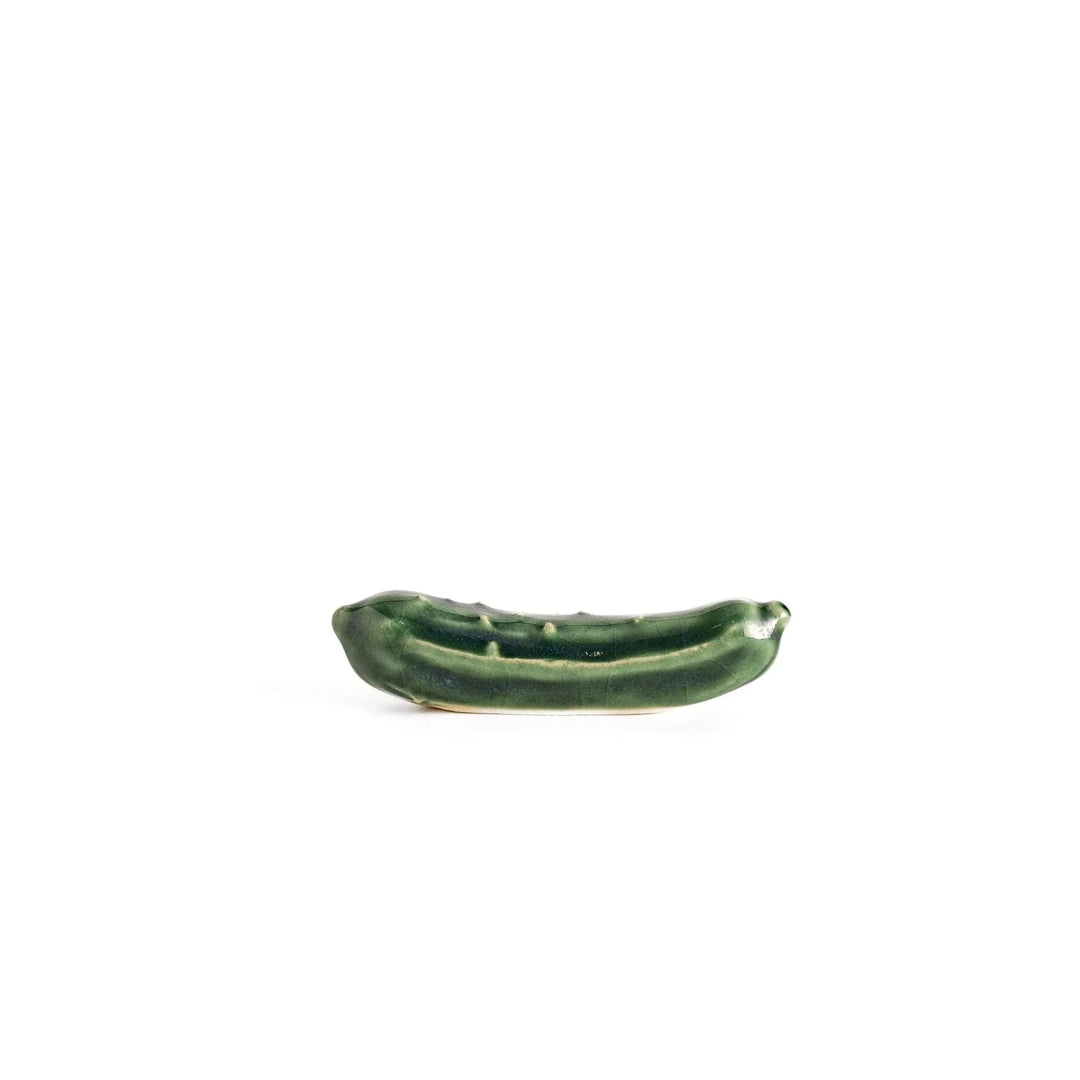 Glossy green ceramic cucumber chopstick rest with textured details adding playful accent to dining table.