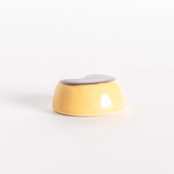 Custard pudding chopstick rest featuring golden caramel color and smooth glossy surface for playful charm.