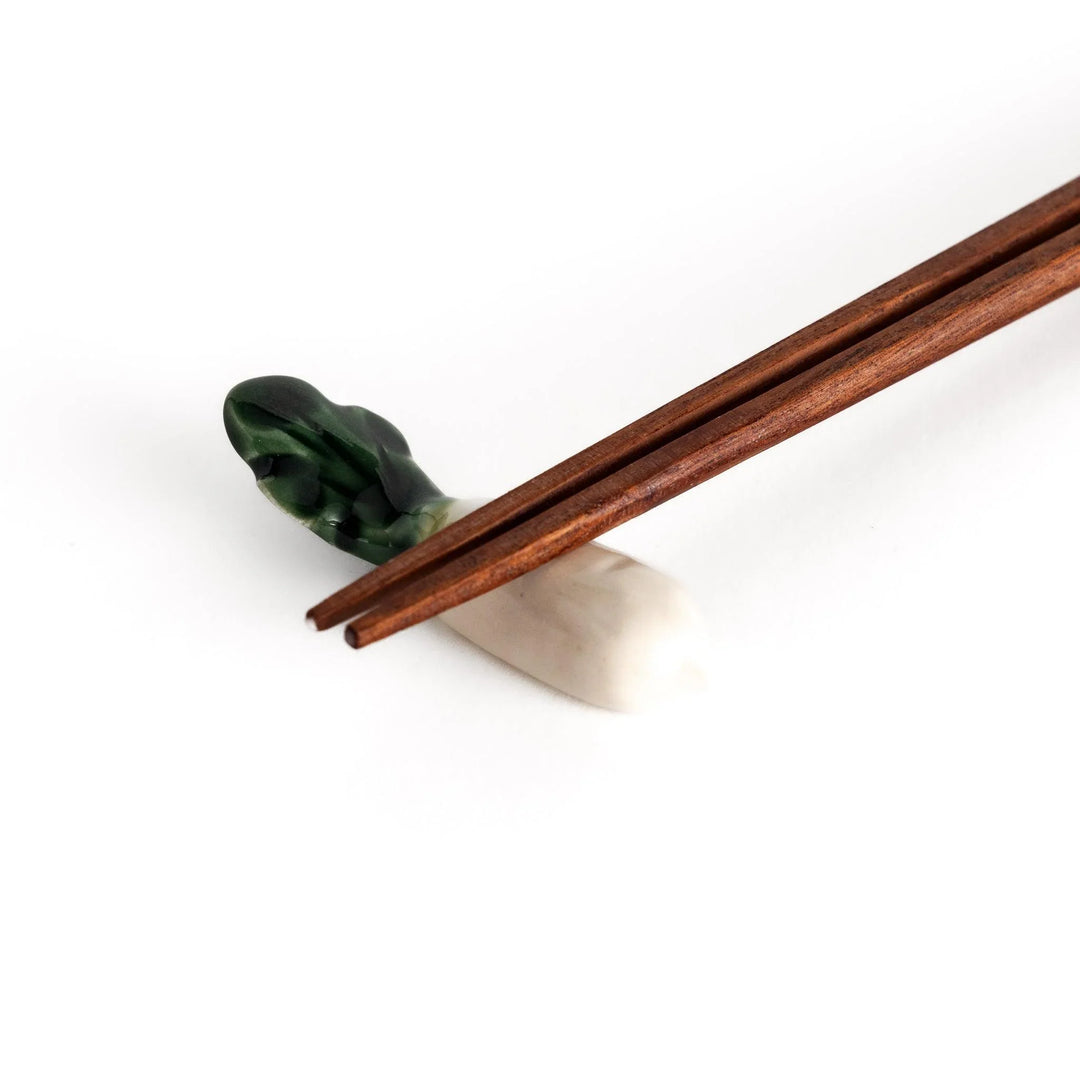 Wooden chopsticks resting on the daikon radish-shaped ceramic chopstick rest, highlighting its elegant and functional design.
