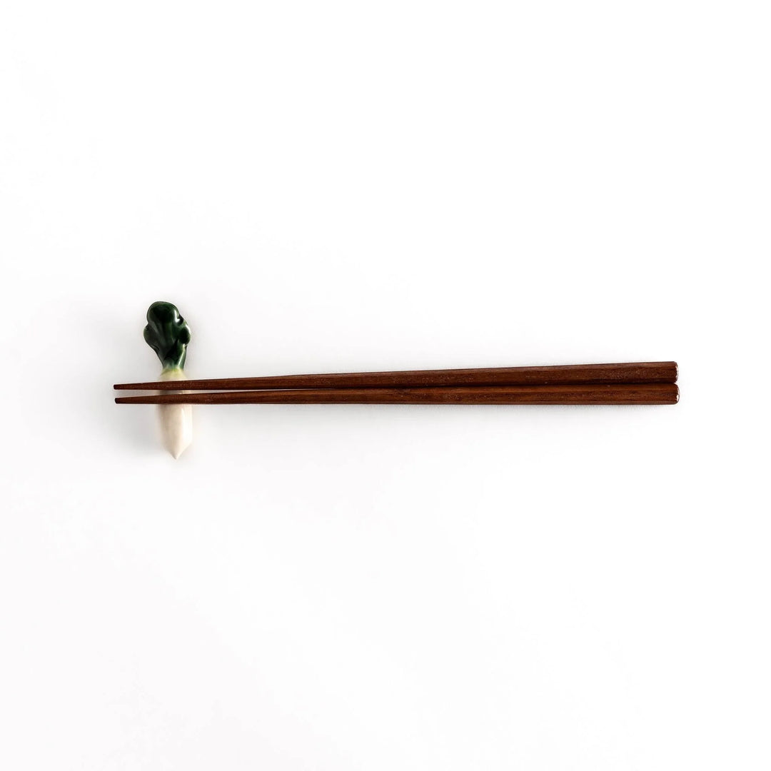 Wooden chopsticks resting on the daikon radish-shaped ceramic chopstick rest, highlighting its elegant and functional design.