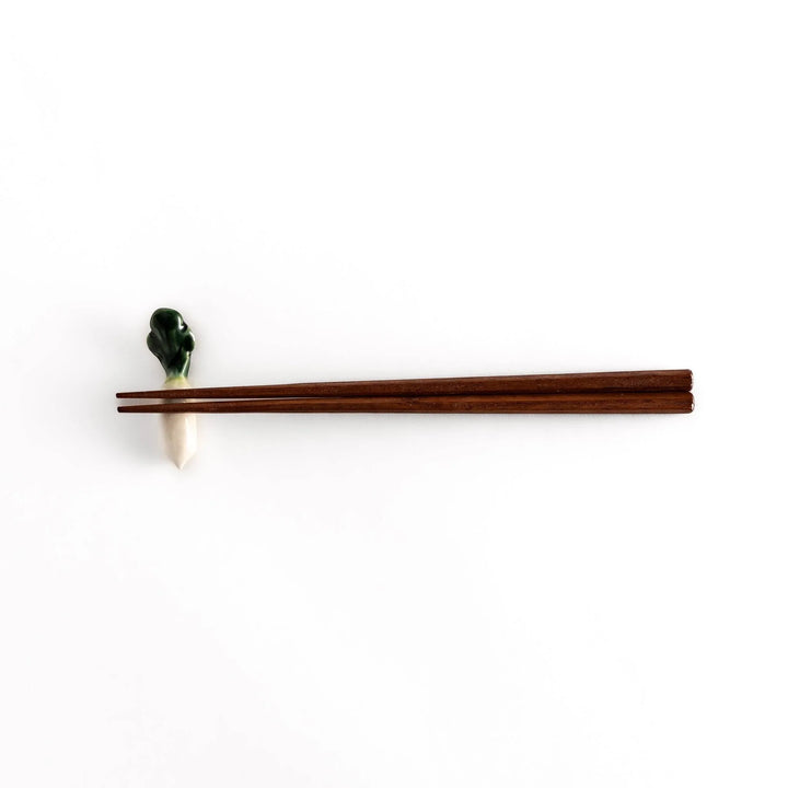 Wooden chopsticks resting on the daikon radish-shaped ceramic chopstick rest, highlighting its elegant and functional design.