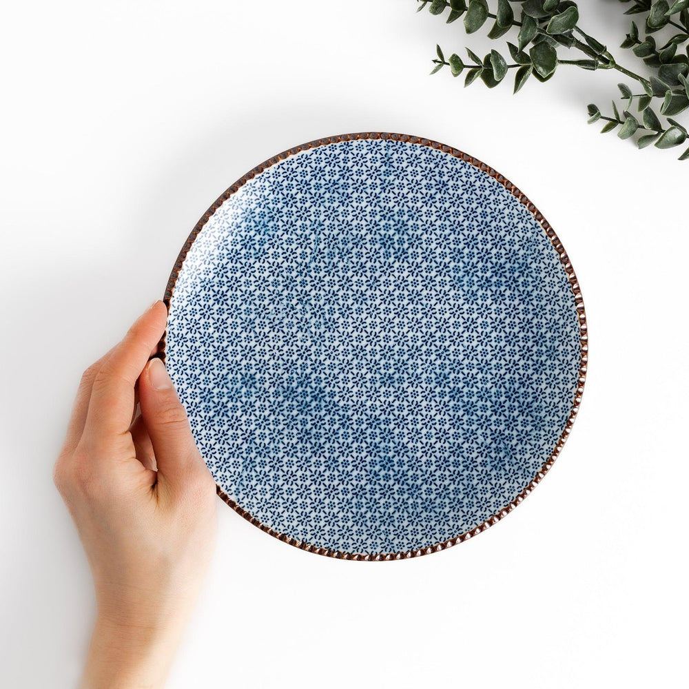 Ceramic plate with intricate blue floral design and bold circular motif framed by copper textured rim.