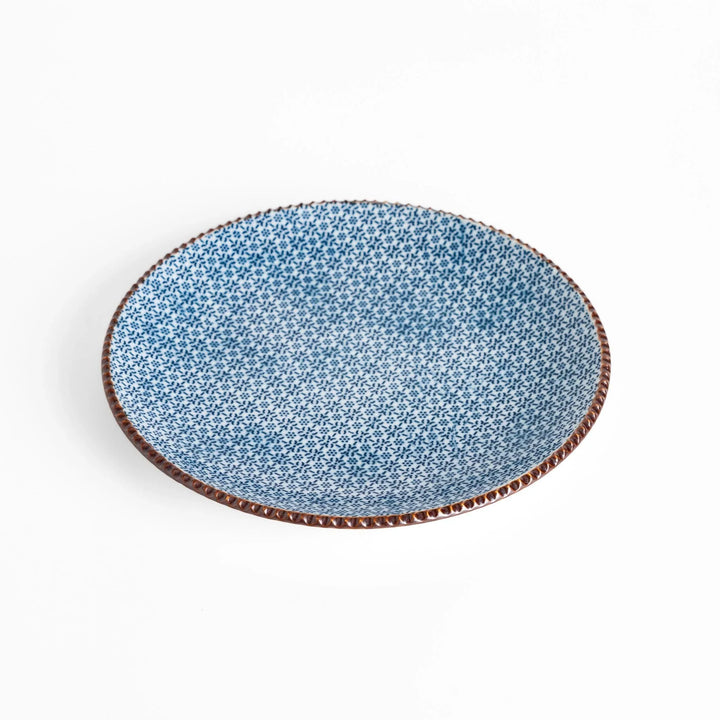 Ceramic plate with intricate blue floral design and bold circular motif framed by copper textured rim.
