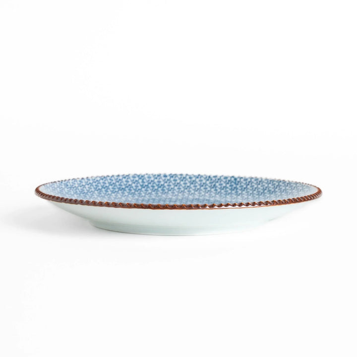 Ceramic plate with intricate blue floral design and bold circular motif framed by copper textured rim.