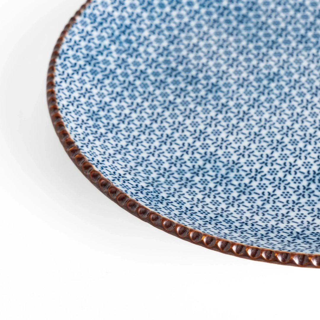 Ceramic plate with intricate blue floral design and bold circular motif framed by copper textured rim.