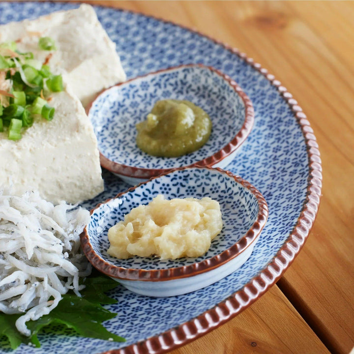 Japanese blue patterned small dishes with grated ginger and yuzu paste beside tofu on Hasami plate.