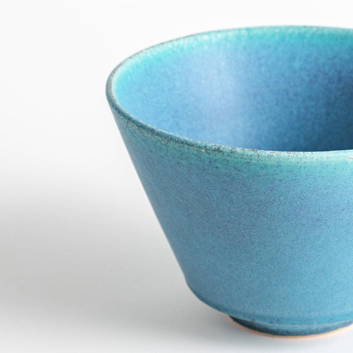 A bowl with a matte turquoise glaze, featuring a minimalist design.