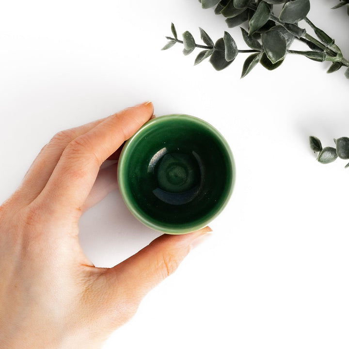 Deep green ceramic sake cup with glossy texture and round shape, perfect for enjoying traditional Japanese sake.