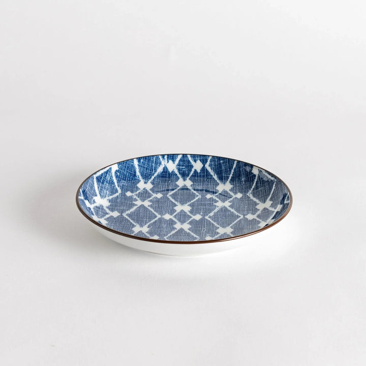 A round dessert plate featuring a bold blue and white lattice pattern.