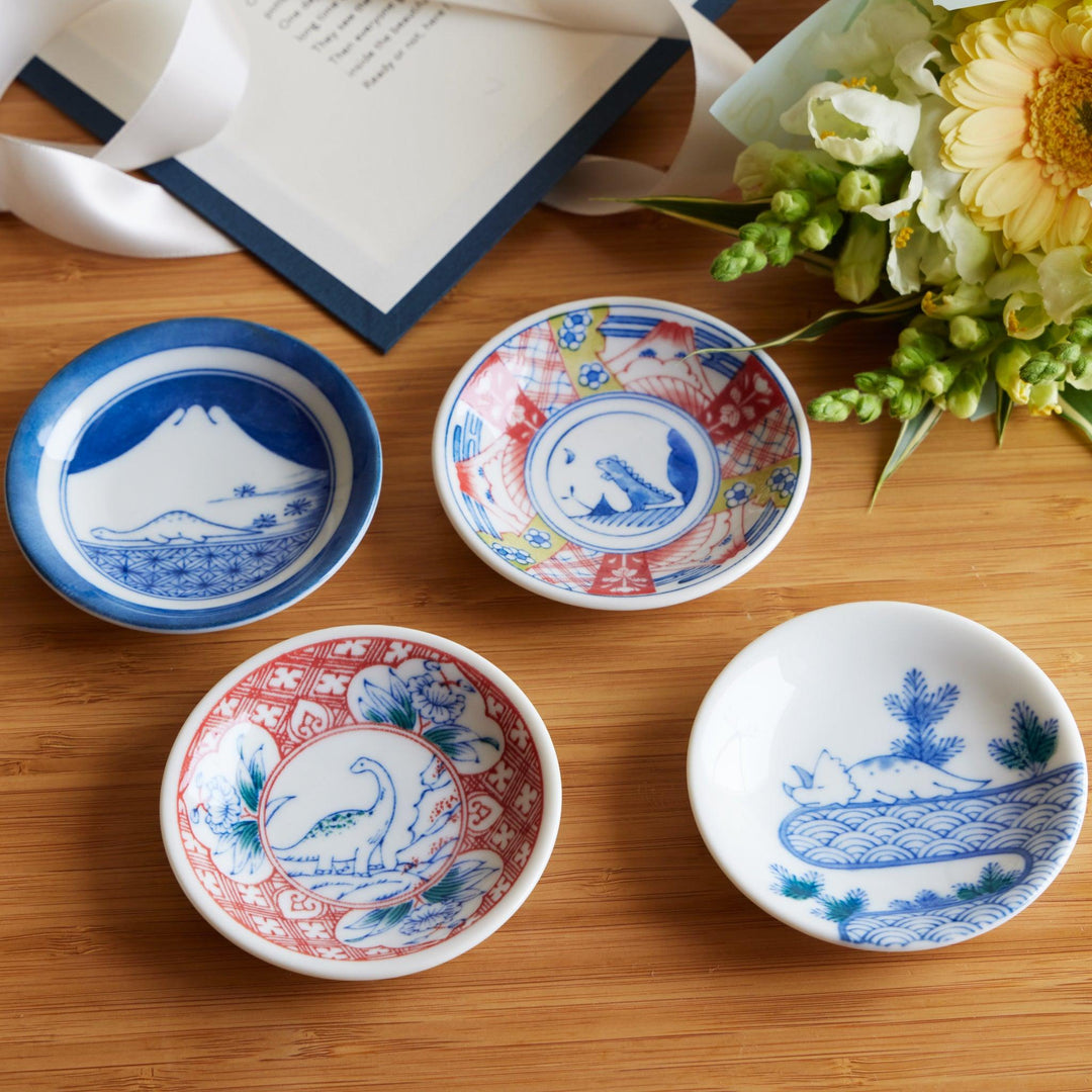 Set of four Japanese sauce dishes with Mount Fuji dinosaur and animal motifs accented with floral designs.