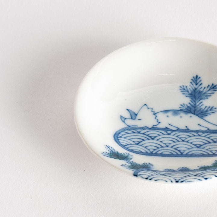 Set of four Japanese porcelain plates in gift box each with blue and red dinosaur design decoration.