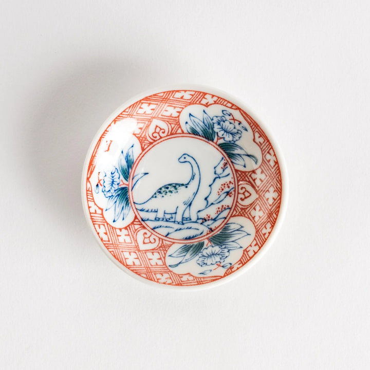 Set of four Japanese porcelain plates in gift box each with blue and red dinosaur design decoration.