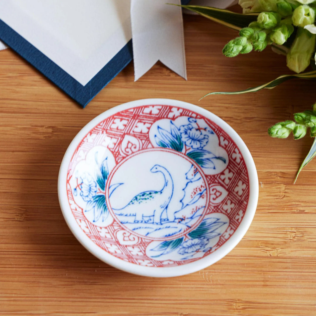 Set of four Japanese porcelain plates in gift box each with blue and red dinosaur design decoration.