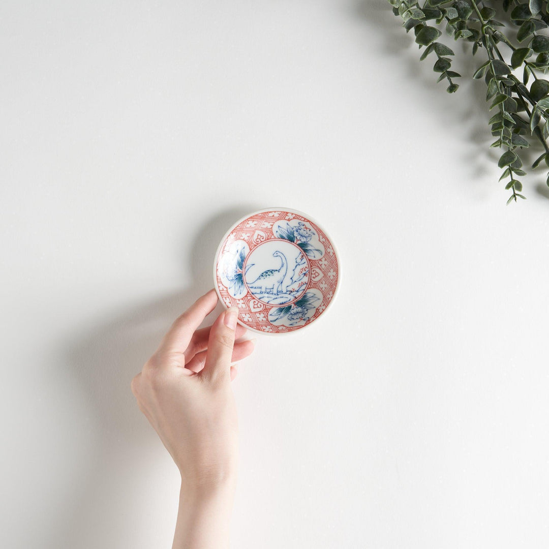 Set of four Japanese porcelain plates in gift box each with blue and red dinosaur design decoration.