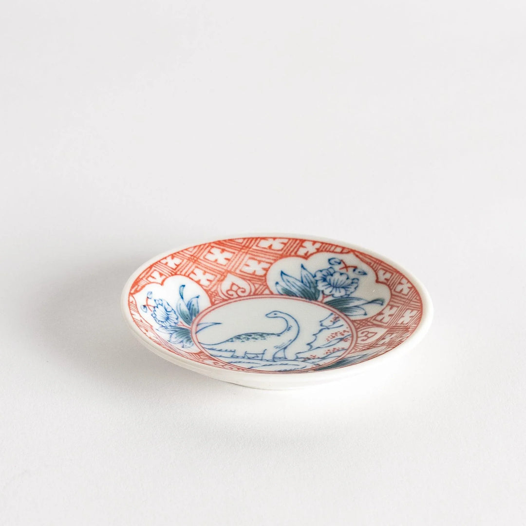 Set of four Japanese porcelain plates in gift box each with blue and red dinosaur design decoration.