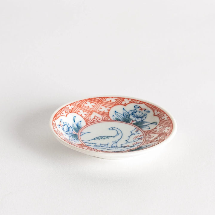 Set of four Japanese porcelain plates in gift box each with blue and red dinosaur design decoration.