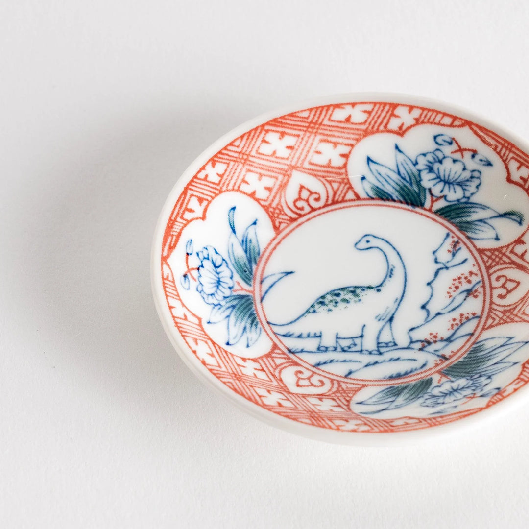 Set of four Japanese porcelain plates in gift box each with blue and red dinosaur design decoration.