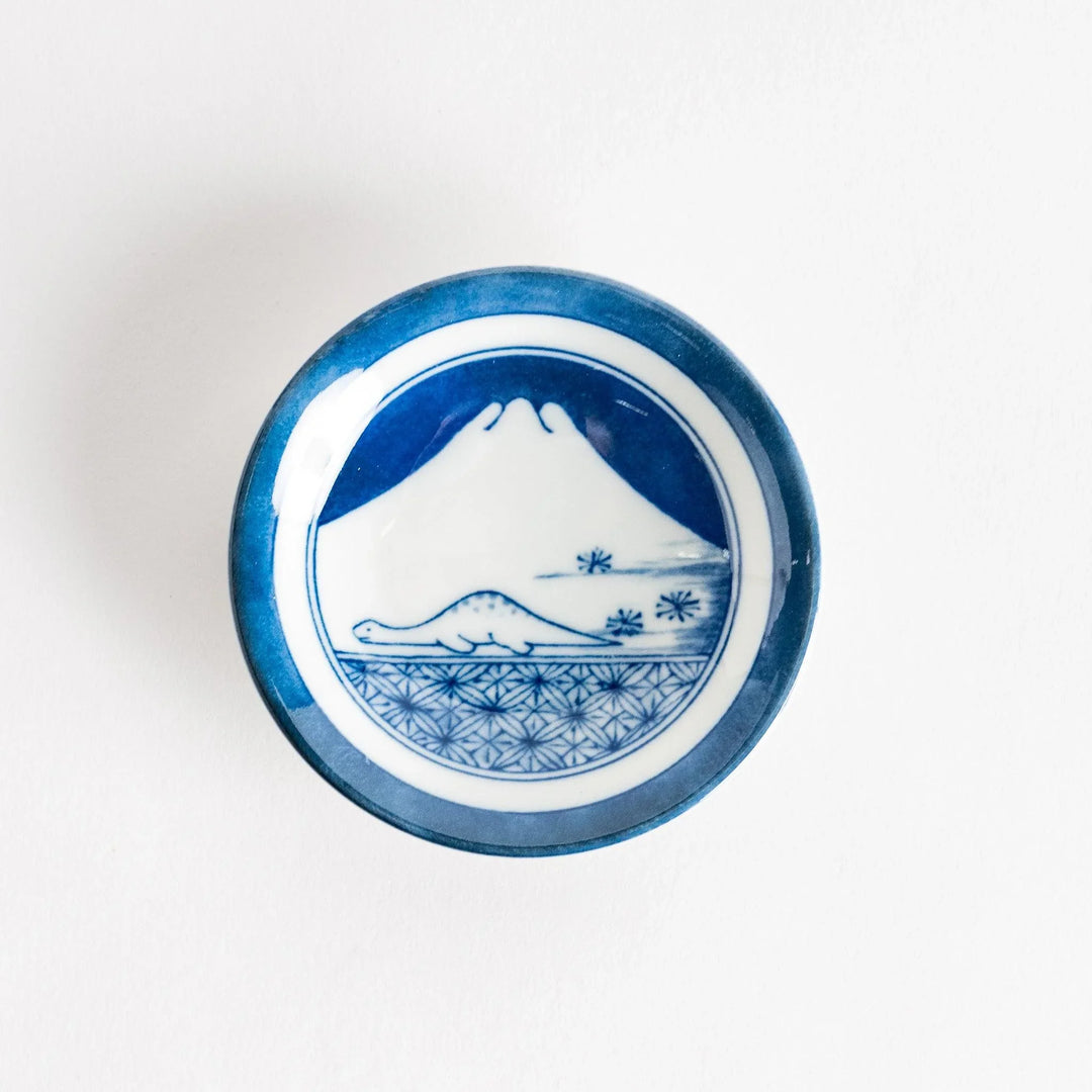 Set of four Japanese porcelain plates in gift box each with blue and red dinosaur design decoration.