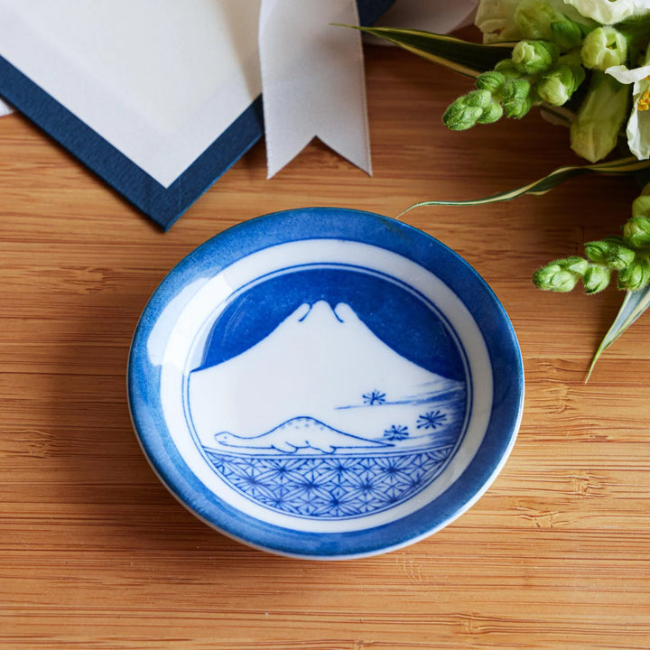 Set of four Japanese porcelain plates in gift box each with blue and red dinosaur design decoration.